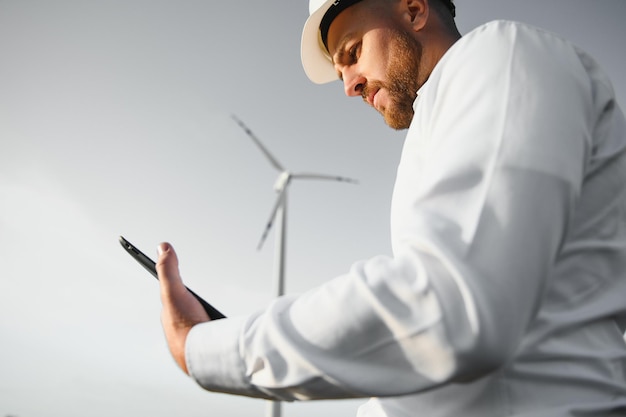 Ingenieros eléctricos que trabajan en la estación generadora de energía de turbinas eólicas con computadora portátil