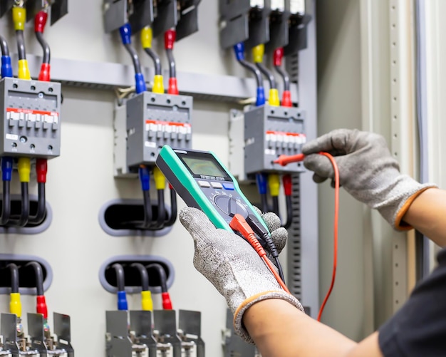 Foto los ingenieros eléctricos verifican los dispositivos de control eléctrico con un multímetro