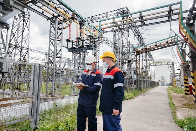 Ingenieros enmascarados inspeccionan una subestación eléctrica