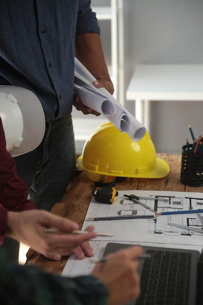 Los ingenieros están consultando al equipo para diseñar una estructura arquitectónica para los clientes con planos y modelos de construcción para trabajar en la oficina