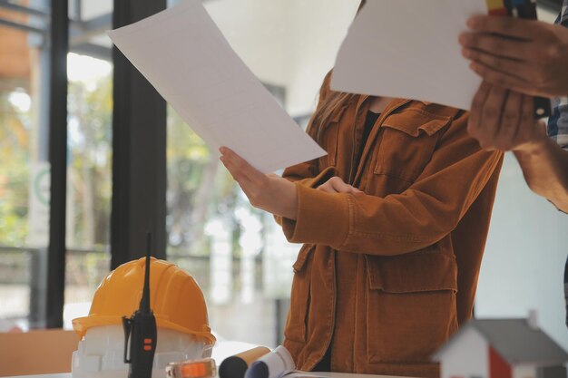 Ingenieros industriales masculinos y femeninos con cascos discuten nuevo proyecto mientras usan una computadora portátil Hacen gestos de exhibiciónTrabajan en una fábrica de fabricación de industria pesada