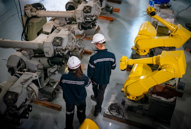 Ingenieros inspeccionando y comprobando la máquina de los robots de soldadura de las armas automáticas en la fábrica