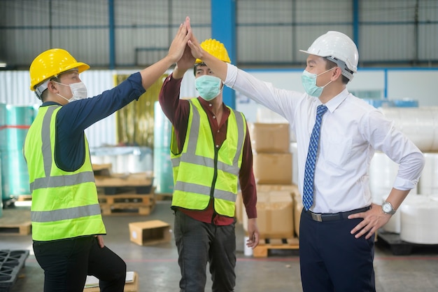 Los ingenieros llevan una mascarilla feliz en la fábrica moderna, el éxito industrial y el concepto de trabajo en equipo