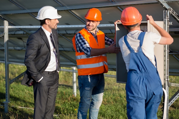 Ingenieros que ofrecen clientes de negocios para mirar la caja eléctrica.