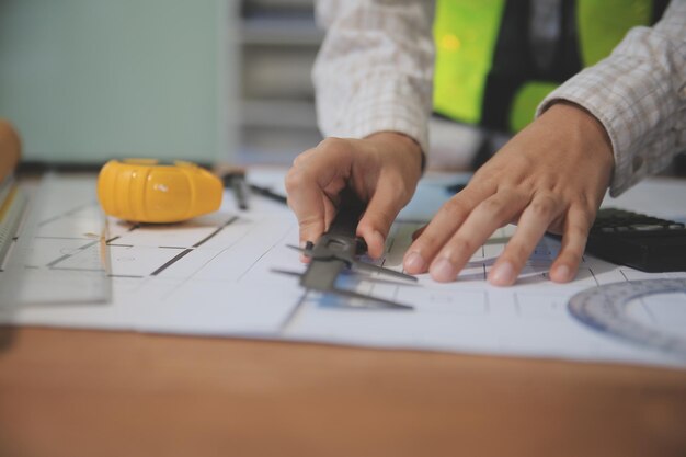 Ingenieros se reúnen trabajando y apuntando a un plan en la oficina para discutir herramientas de ingeniería y concepto de construcción