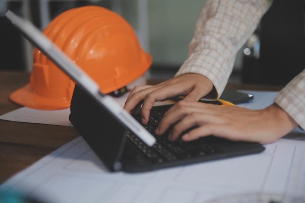 Ingenieros se reúnen trabajando y apuntando a un plan en la oficina para discutir herramientas de ingeniería y concepto de construcción