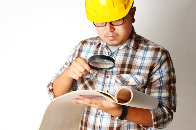 Los ingenieros sostienen el papel de construcción usando una lupa para buscar detalles para mayor precisión.