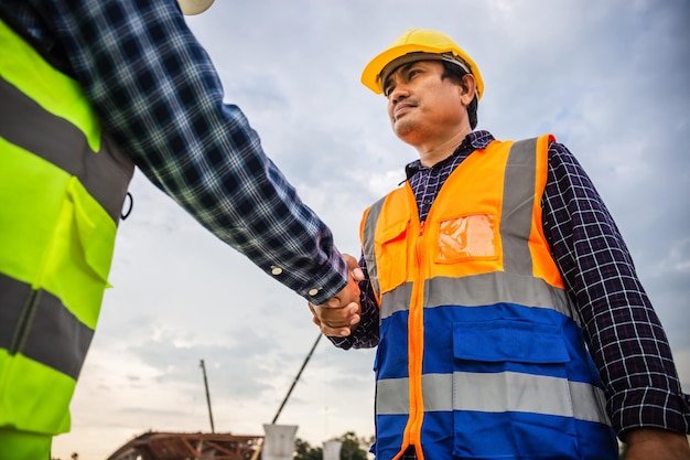 Ingenieros y trabajadores de la construcción dándose la mano en el sitio de construcción