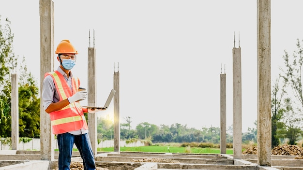 Ingenieur-Auftragnehmer verwenden Laptop-Arbeitsindustrie-Projekt-Check-Plan-Design in Hochbau-Baustelle