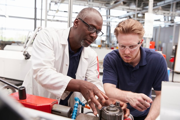 Ingenieur berät einen männlichen Lehrling in einer Fabrik aus nächster Nähe