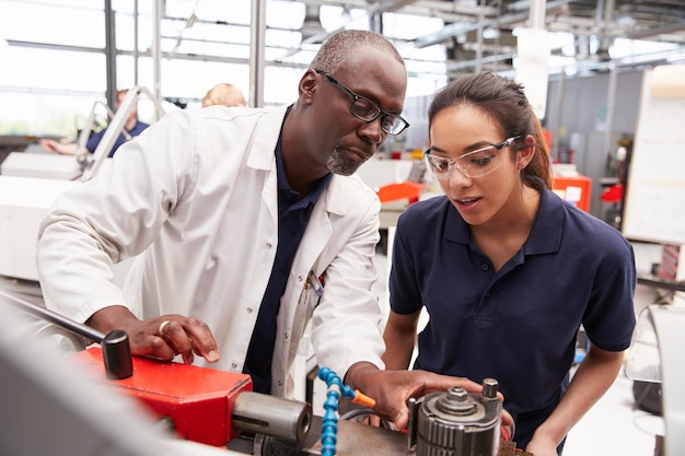 Ingenieur, der einem weiblichen Lehrling die Ausrüstung aus nächster Nähe zeigt