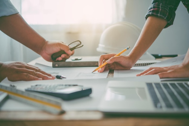 Foto ingenieur, der im büro mit blaupausen arbeitet, inspektion am arbeitsplatz für architekturplan, bauprojekt, geschäftsaufbau