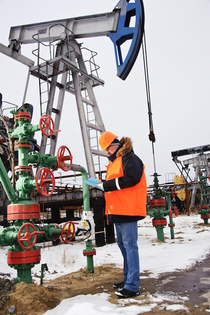 Ingenieur in orangefarbener Uniform und Helm auf dem Hintergrund der Pumpenbuchse.