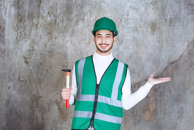 Ingenieur Mann in gelber Uniform und Helm hält eine Axt mit Holzgriff zur Reparatur.