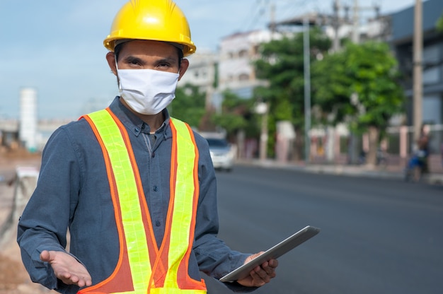 Ingenieur mit einer medizinischen Maske und Tablette