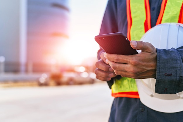 Ingenieur mit Helm und Telefon senden Arbeitsdatenbericht