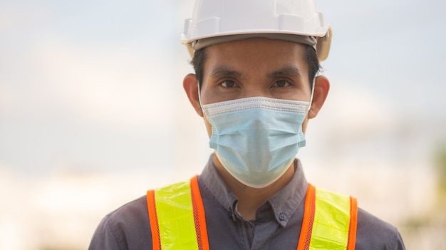 Ingenieur trägt eine medizinische Maske, schützt das Covid19-Coronavirus und arbeitet im Freien