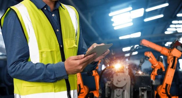 Ingenieur verwendet fortschrittliche Robotik-Software, um den Industrieroboterarm in der Fabrik zu steuern