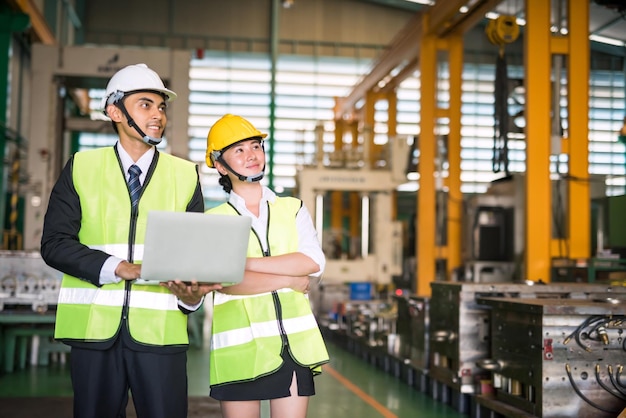 Ingenieure halten einen Laptop und schauen in der Fabrik weg