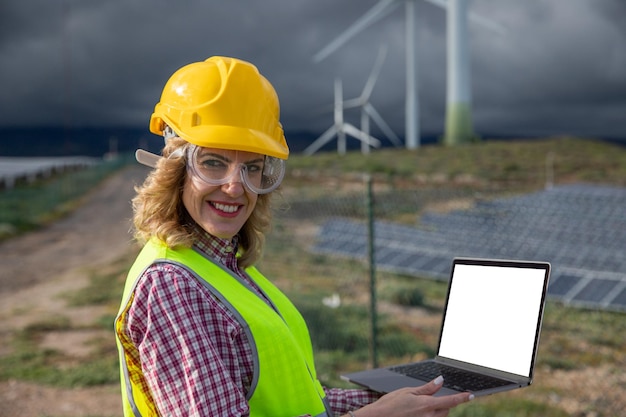 Ingenieurin benutzt ihren Laptop, während sie im Bildschirm eines Solarkraftwerks mit Mockup arbeitet