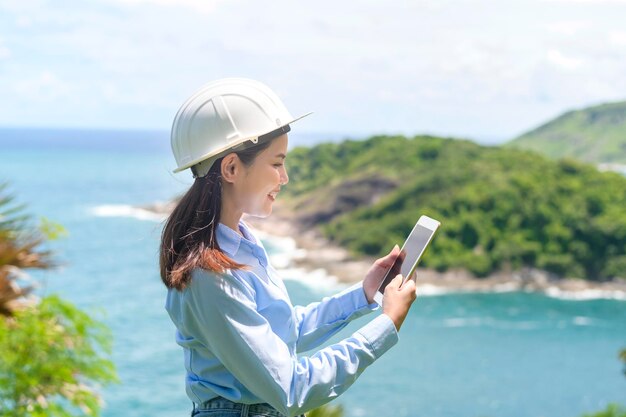 Ingenieurin, die am Meer arbeitet und einen Schutzhelm x9 trägt