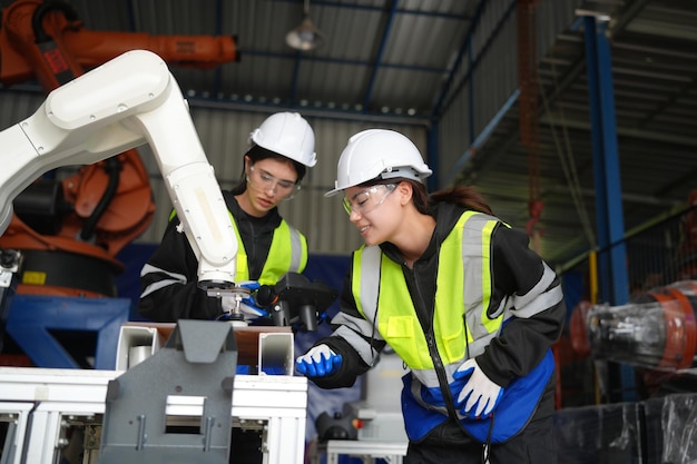 Ingenieurin überprüft und steuert Automatisierungsroboterarme in intelligenter Fabrikindustrie auf Echtzeitüberwachungssystem-Softwarerobotik und digitalem Fertigungsbetrieb