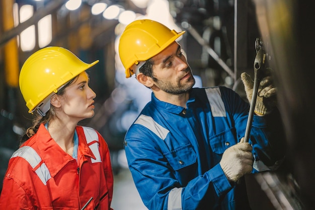 Foto ingenieurin und arbeiterin, die geräte in der fabrik auf reparatur überprüft