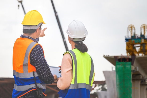 Ingenieurin und Vorarbeiter überprüfen Projekt auf der Baustelle Ingenieur und Bauarbeiter in Hardhats diskutieren auf der Baustelle Teamwork-Konzepte