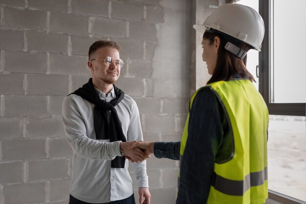 Ingenieurinnen und Ingenieure in weißen Helmen und gelben Warnwesten auf der Baustelle zu construction