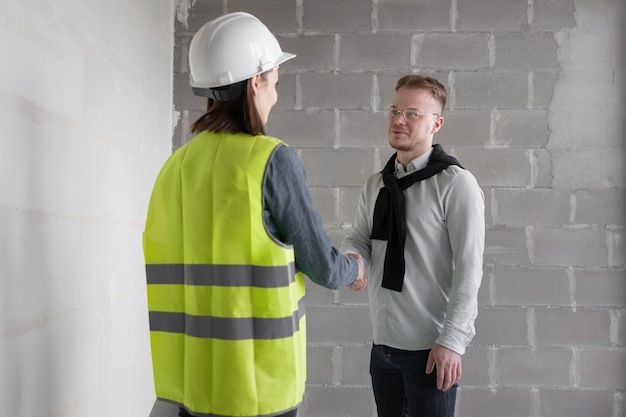 Ingenieurinnen und Ingenieure in weißen Helmen und gelben Warnwesten auf der Baustelle zu