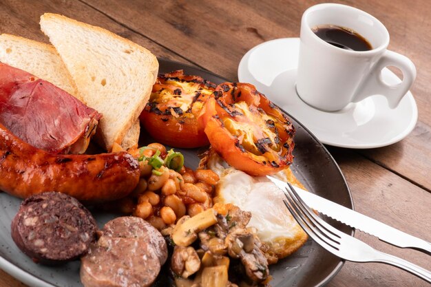 Inglés irlandés Reino Unido desayuno plato con muchas proteínas frijoles dulces y una taza de café de cerca