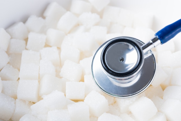 Foto ingrediente alimentar doce em cubo de açúcar e estetoscópio médico