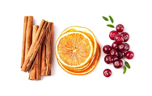 Ingrediente de especiarias em fundos brancos. vagens de canela, frutas secas de laranjas e cranberries em fundo branco. ingrediente de vinho quente.