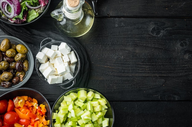 Ingrediente de salada grega cozinhando, em fundo preto de mesa de madeira com espaço de cópia para o texto