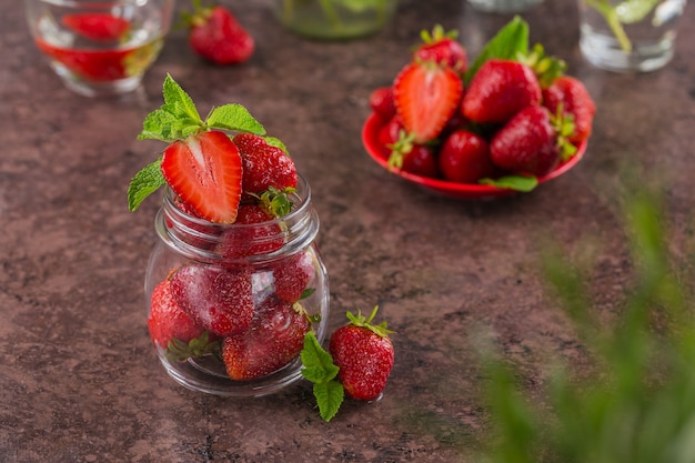 Ingrediente para compota de morango caseira ou marmelada em frasco de vidro com frutas doces maduras e folhas de hortelã