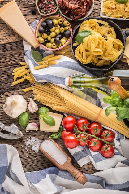 Foto ingredientes alimentares italianos massas azeite de oliva queijo parmesão manjericão alho cogumelos tomates azeitonas em mesa de madeira