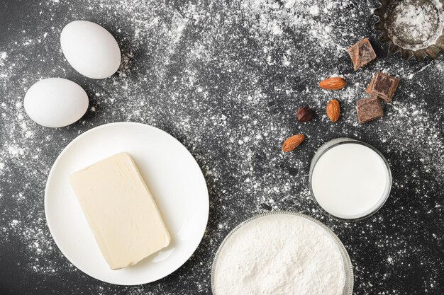 Los ingredientes de alimentos crudos para hornear y la forma de cupcakes sobre fondo oscuro se preparan para cocinar la vista superior