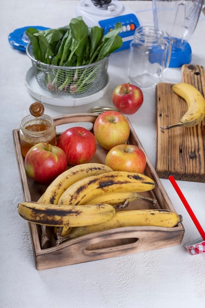 Ingredientes de batido de frutas con espinacas en primer plano de la mesa. Plátanos, manzanas, espinacas, miel