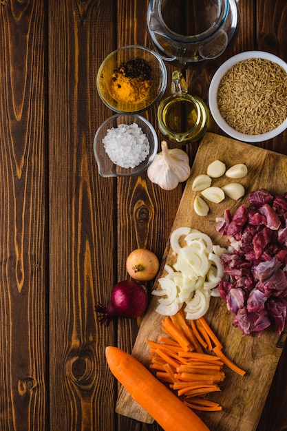 Foto ingredientes carne con arroz cocinando en una mesa de madera