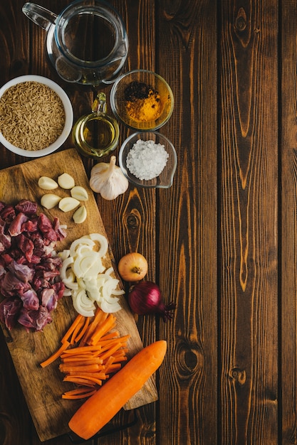 Foto ingredientes carne con arroz cocinando en una mesa de madera