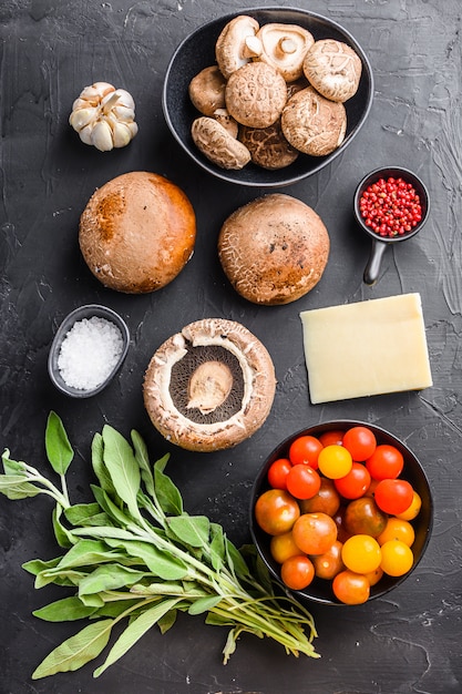 Ingredientes de champiñones al ajillo, queso cheddar portabello y salvia para hornear sobre fondo negro. Vista superior.