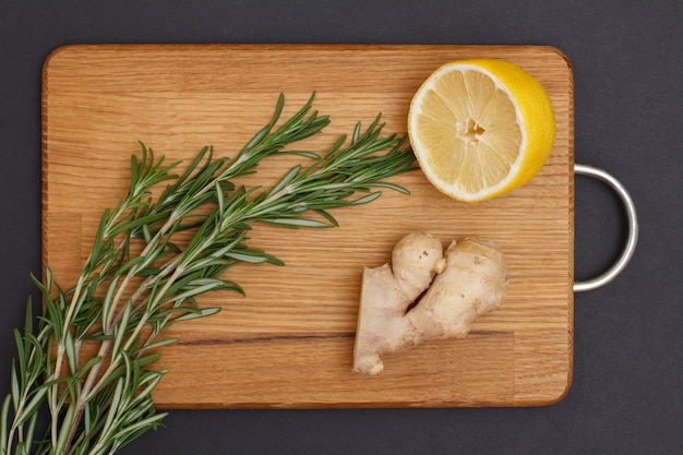 Ingredientes para cocinar carne o pescado. Raíz de jengibre, limón y romero sobre una tabla para cortar madera. Vista superior.