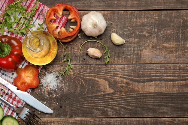 Ingredientes para cocinar ensalada. Varias verduras y especias zanahorias, tomates, pepinos, pimientos y rúcula en una mesa de madera marrón. vista superior.