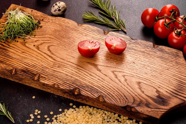 Foto ingredientes para cocinar pasta sobre un fondo oscuro tomates de cereza especias y hierbas preparadas para pasta