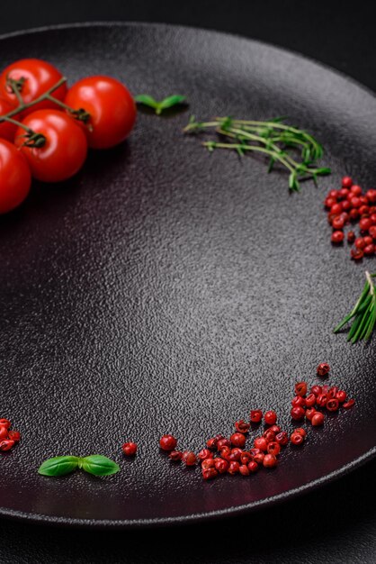 Ingredientes para cocinar tomates cherry sal especias y hierbas sobre un fondo de hormigón oscuro