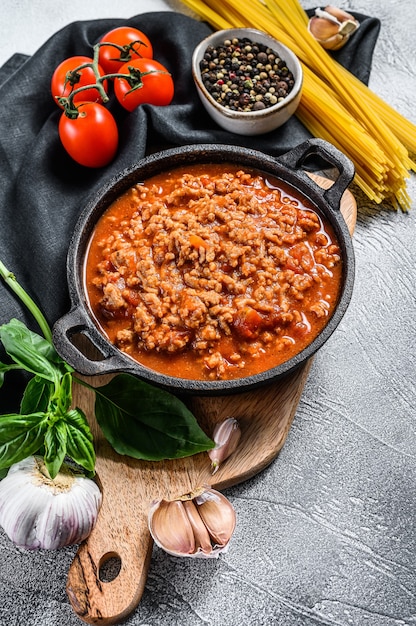 Foto ingredientes de la comida italiana para espaguetis a la boloñesa. pasta cruda, albahaca, carne molida, tomates
