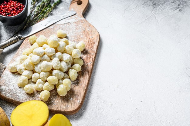 Ingredientes de comida de ñoquis: ñoquis frescos, aceite de oliva, papas y tomillo. Fondo gris Vista superior. Copia espacio