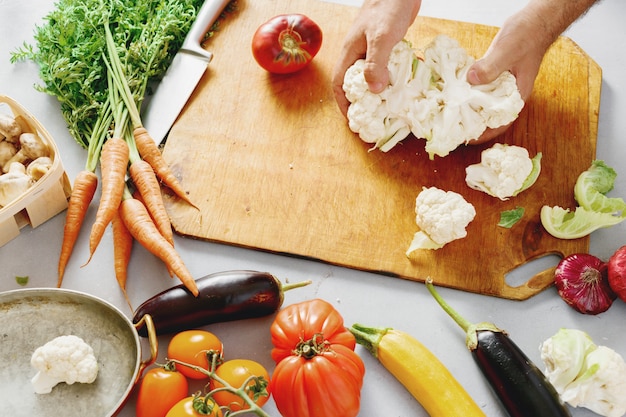 Ingredientes crudos para cocinar verduras guisadas El hombre prepara un plato vegetariano de verduras