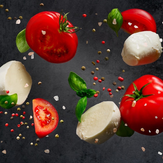 Ingredientes da salada caprese caindo no aperitivo italiano de fundo escuro