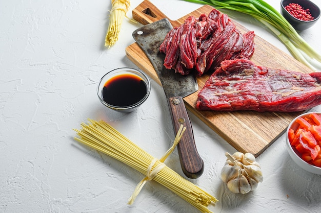 Ingredientes de cozinha para fazer yakissoba frito com carne. vista lateral na mesa branca com espaço para texto.